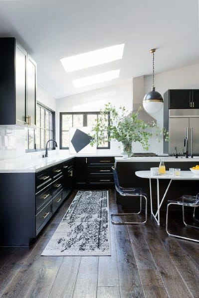 Black kitchen cabinets with white countertops, hardwood floors, skylights, and a dining nook.