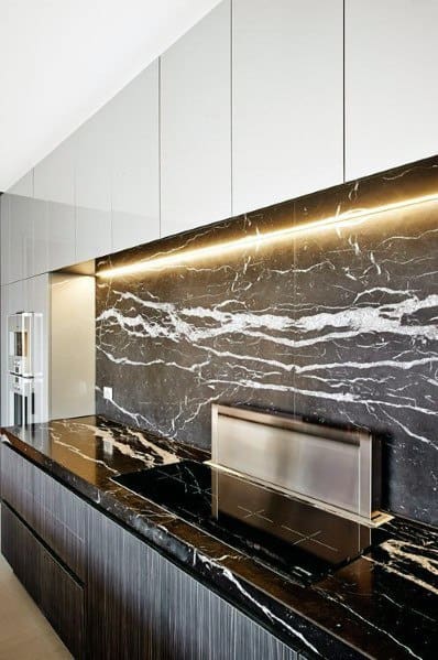 Luxurious kitchen with a black marble backsplash and countertop, accented by white veining and warm LED lighting