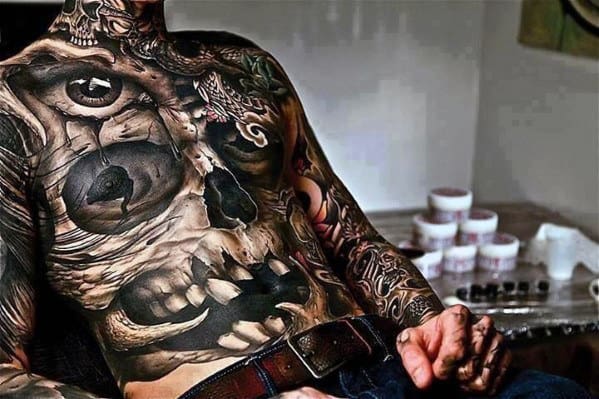 Extensive chest and arm tattoos, including an eye and skull design