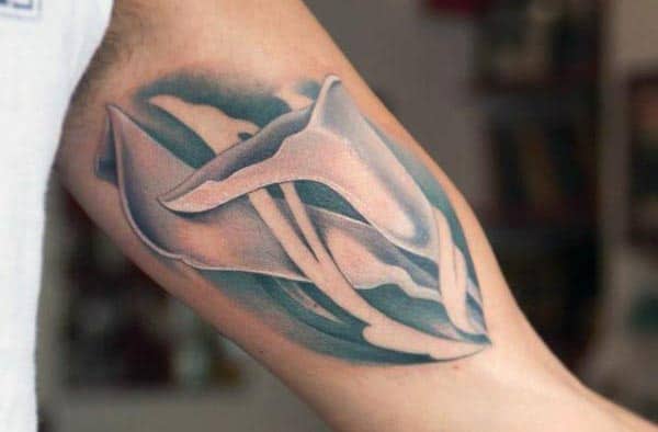 Abstract tattoo of flowing, ribbon-like shapes in shades of blue and white, creating a smooth, fluid design on the inner bicep