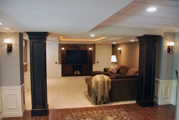Cozy basement living room with dark wood columns and warm ambient lighting.