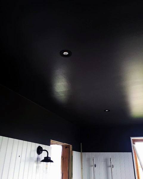 Bathroom with dark painted ceiling, white tiled walls, and recessed lighting.