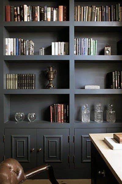Dark blue bookshelf with books, decorative items, glass bottles, and closed lower cabinets