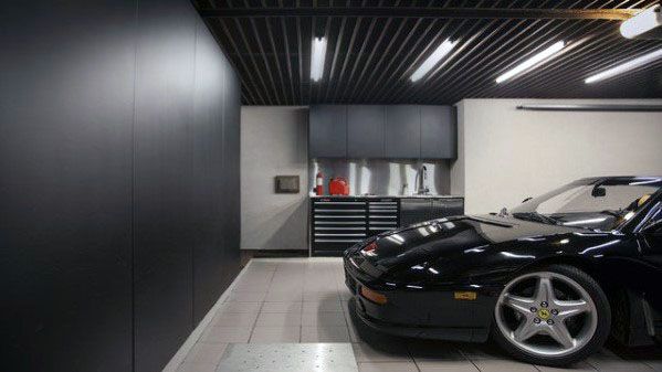Luxury garage with black slatted ceiling, bright lighting, and a sleek black sports car.
