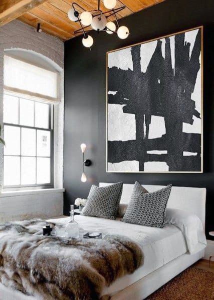 Modern bedroom with black accent wall, large abstract artwork, and white bedding.