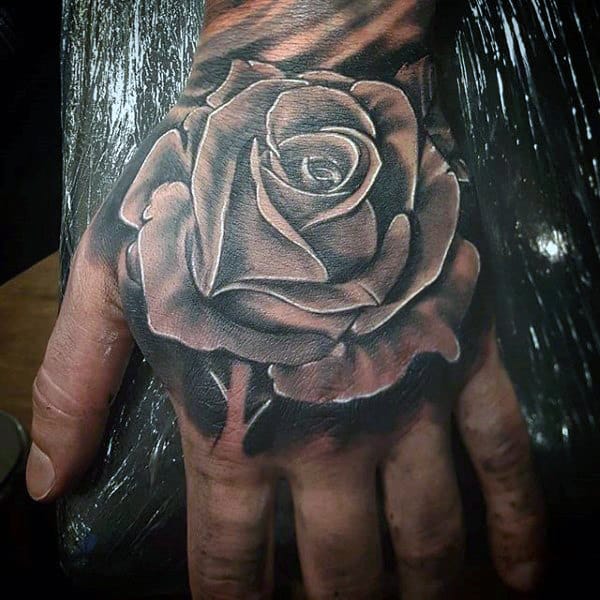 Black and white rose tattoo on the back of a hand