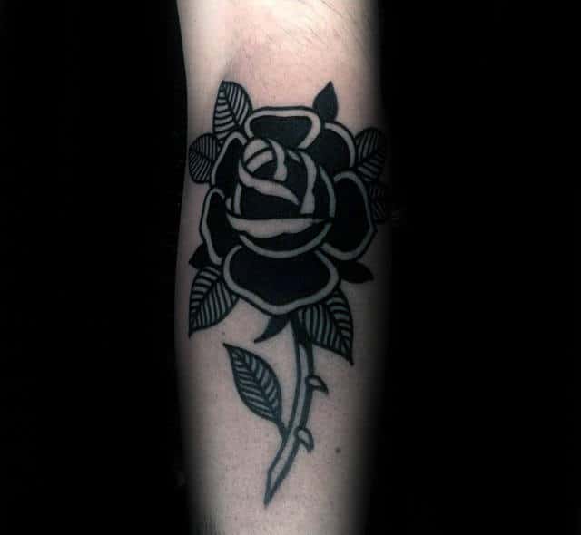 Tattoo of a stylized black rose with leaves on an arm