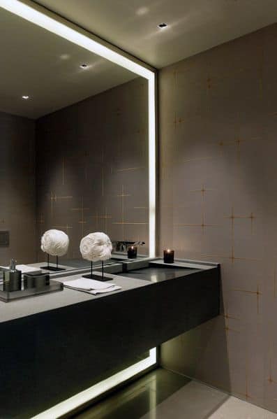Modern bathroom with LED-lit mirror, dark vanity, and decorative skull art.