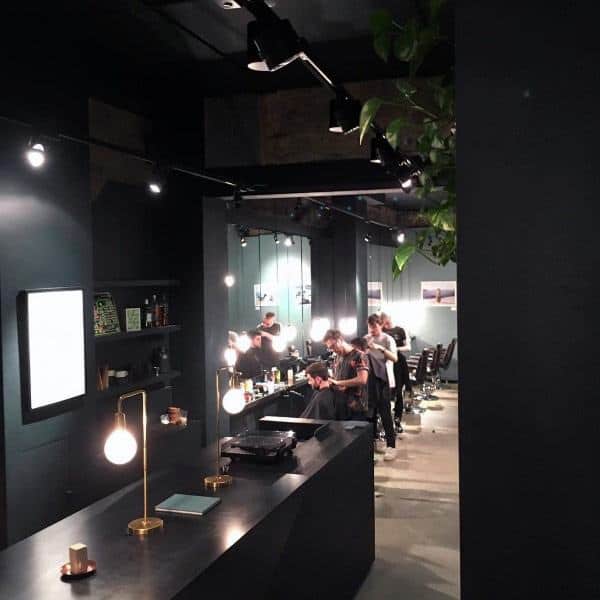 Modern barbershop with sleek black interiors, ambient lighting, and minimalist decor.