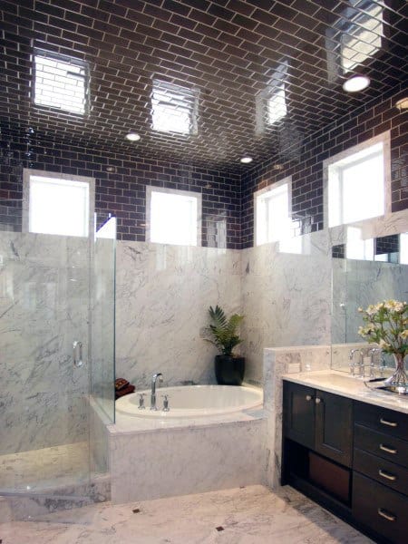 Luxury bathroom with black beveled tile ceiling, marble walls, and built-in bathtub.