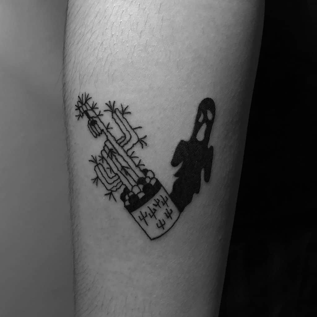 A black ink tattoo of a potted cactus with an eerie ghostly shadow emerging from it, blending nature with a spooky, surreal element.
