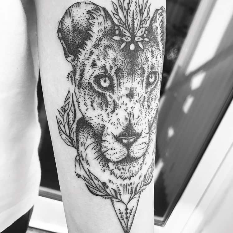 Detailed lioness tattoo on the forearm, featuring dotwork shading, floral accents, and geometric elements for an artistic, elegant design.