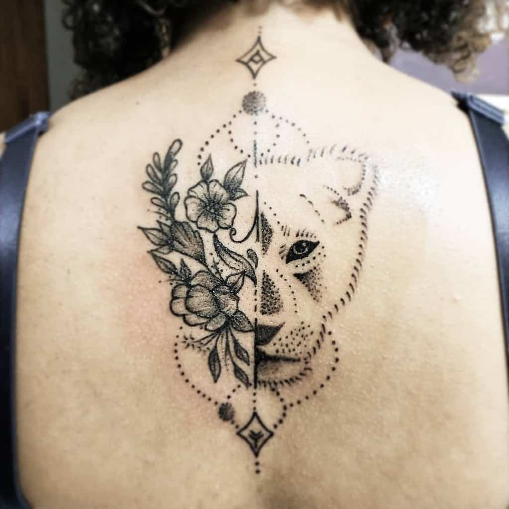 Elegant back tattoo featuring a half-lioness face with fine floral details on one side and geometric dotwork symmetry on the other.