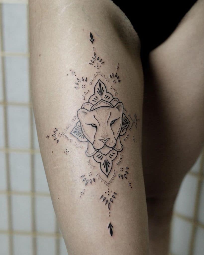 Minimalist mandala-style lioness tattoo on the thigh, featuring fine linework, geometric symmetry, and delicate ornamental details.