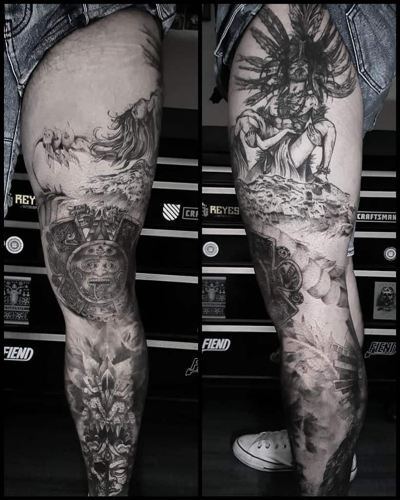 Black and grey tattoo leg sleeve, featuring intricate designs such as tribal man with feathers in his head holding a woman, a detailed skull with mask, and other symbolic elements