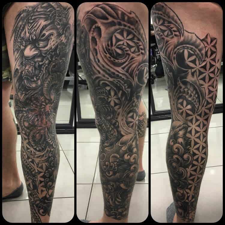 Intricate black and grey full-leg sleeve tattoo featuring a fierce creature, floral patterns, and geometric designs from various angles