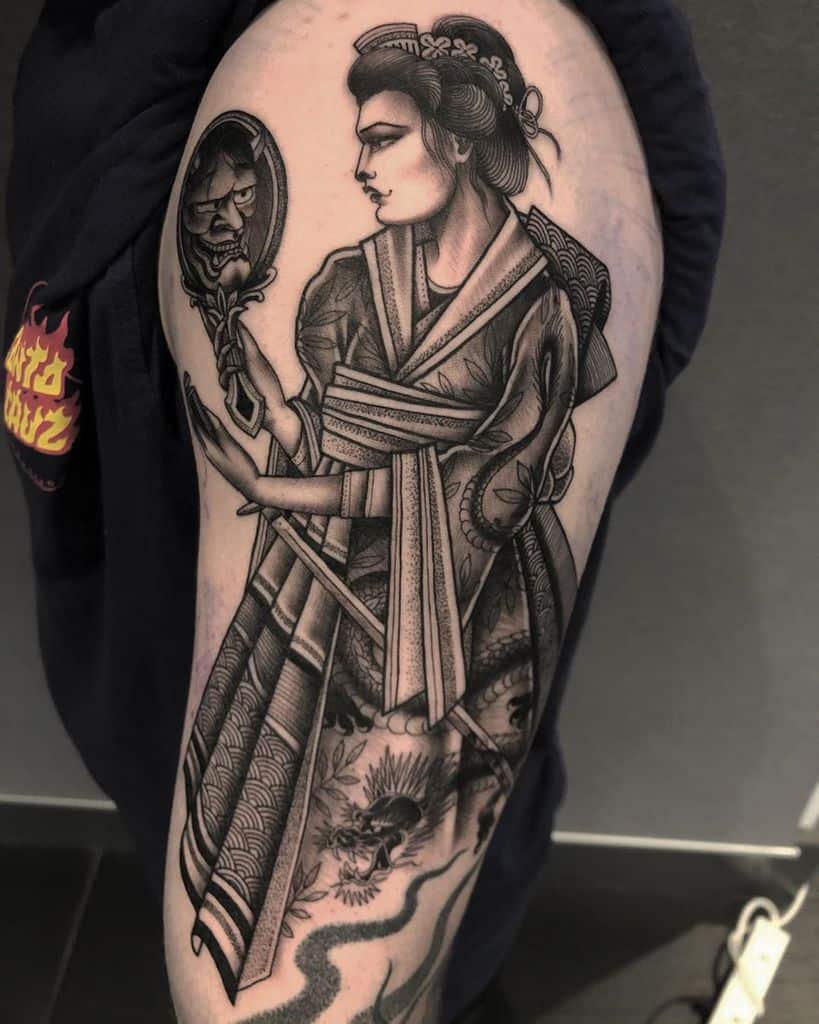 Black and grey tattoo of a Geisha in a detailed kimono, holding a mirror reflecting a demonic face, blending traditional and eerie elements.