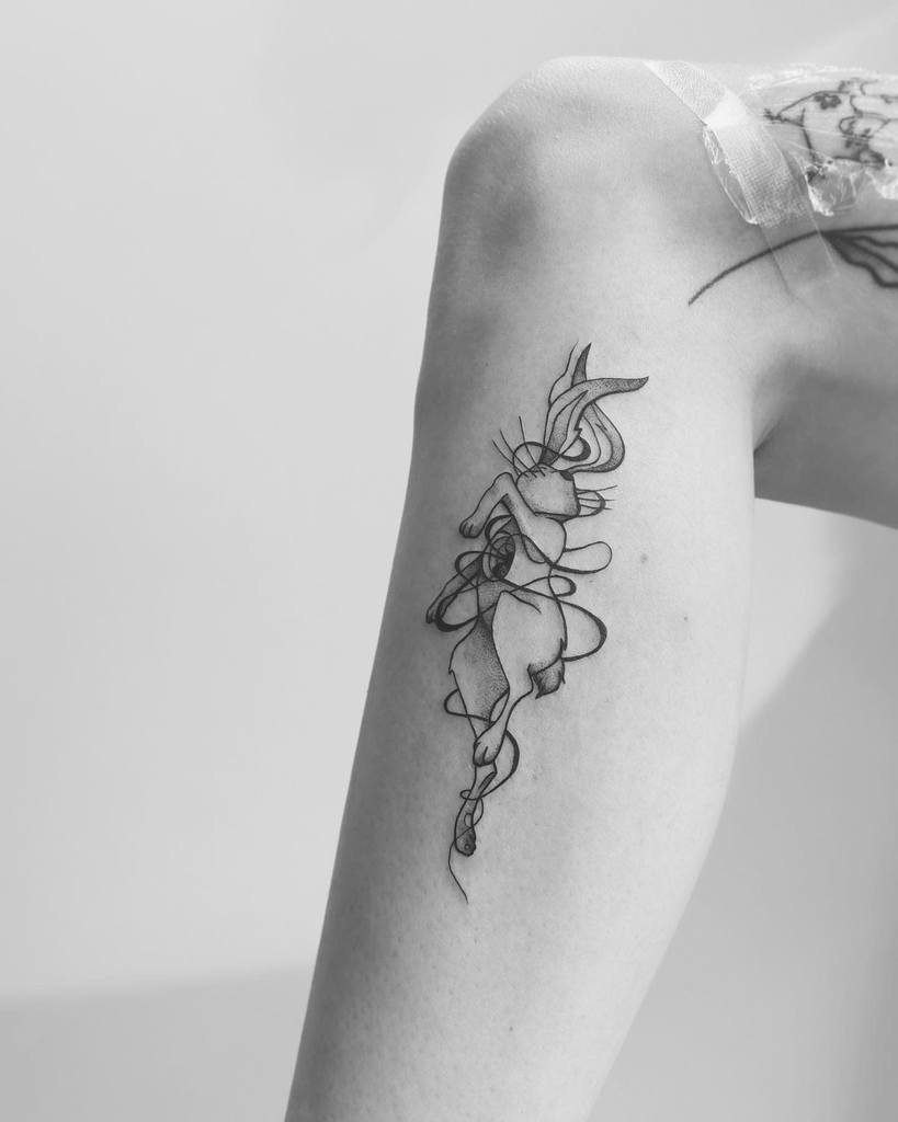 Black and white tattoo of a rabbit, depicted with fluid lines and abstract shapes