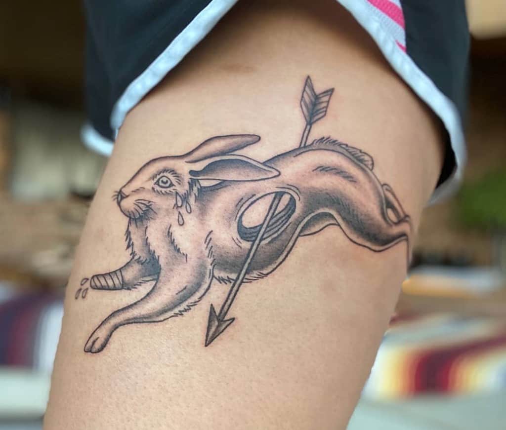 Tattoo of a leaping rabbit with an arrow piercing through its body, and a tear under its eye