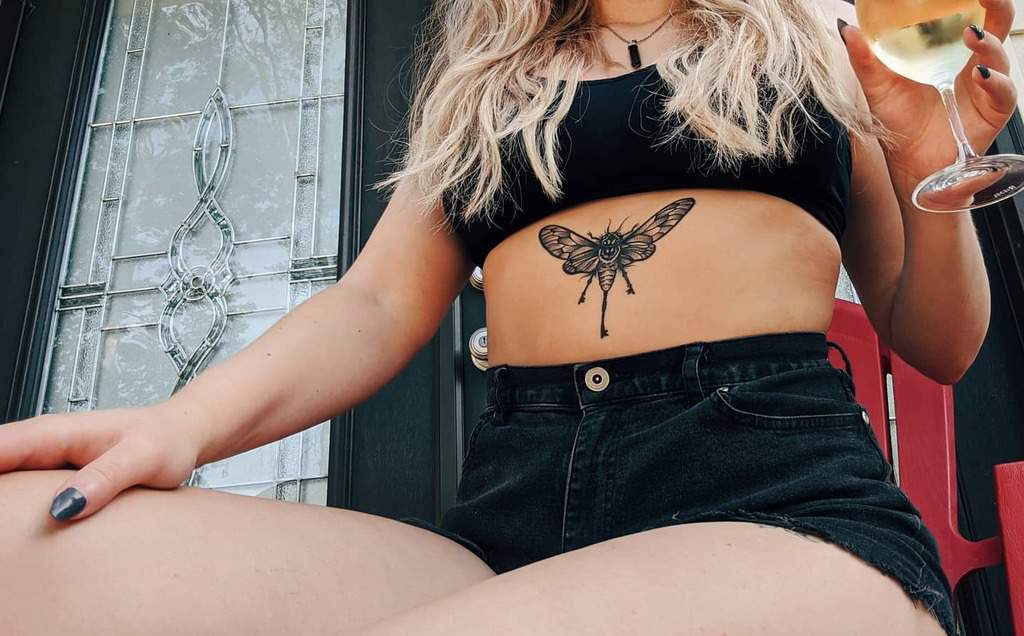 Blackwork cicada tattoo on the lower abdomen, featuring detailed wings and bold linework for a striking design.