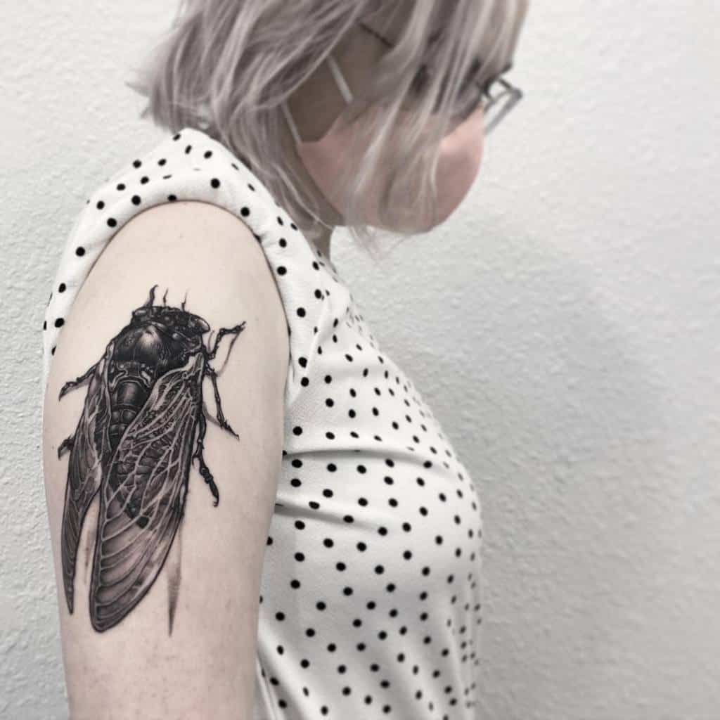 Woman with cicada tattoo on upper arm