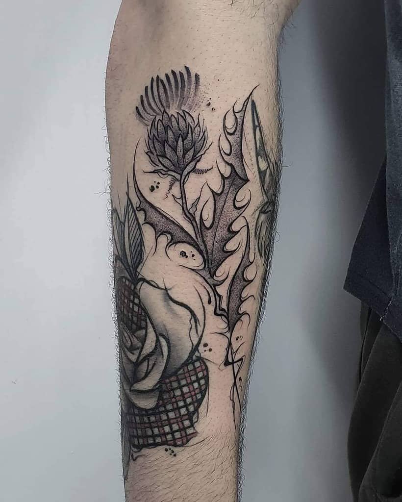 Intricate blackwork tattoo featuring a thistle flower, flowing abstract designs, and textured shading on the forearm