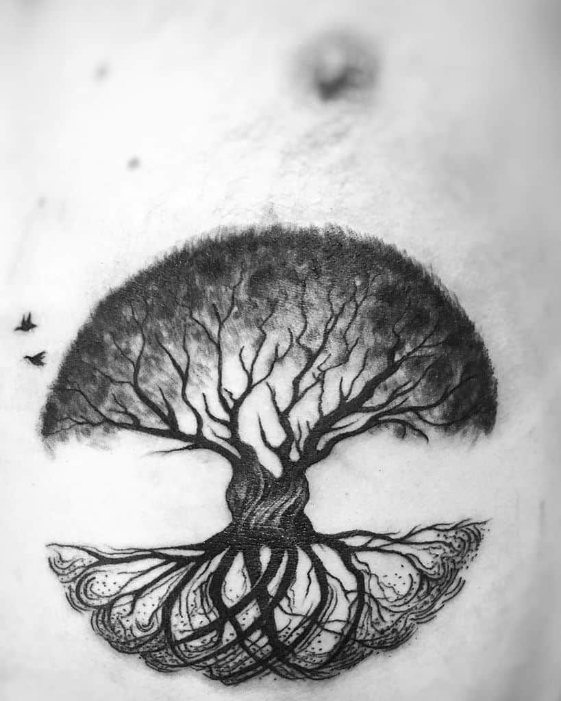 Blackwork tattoo of a tree of life with intricate roots and branches forming a semicircle, accented by flying birds