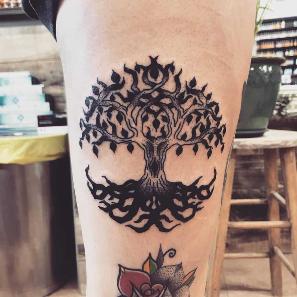 Blackwork tattoo of a stylized tree of life with intricate symmetrical patterns in the branches and roots