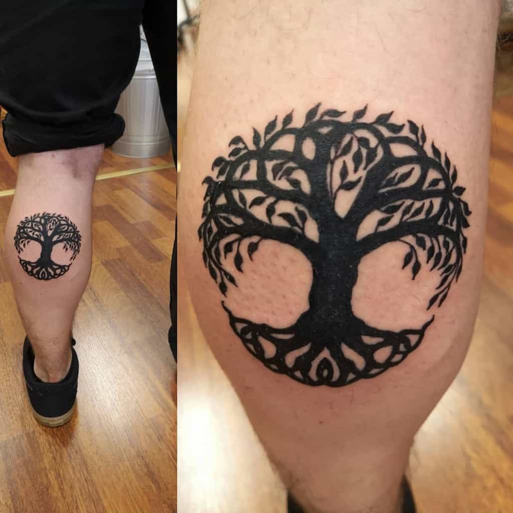 Bold blackwork calf tattoo featuring a circular tree of life with intricate branches and roots in a symmetrical design