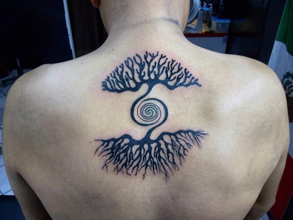 Back tattoo featuring two mirrored trees with intricate roots and branches connected by a central spiral design