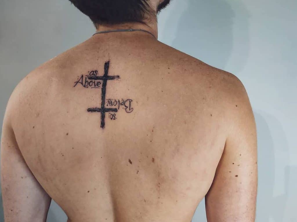 Minimalist back tattoo featuring the text 'As Above, So Below' arranged around a cross, symbolizing balance and duality