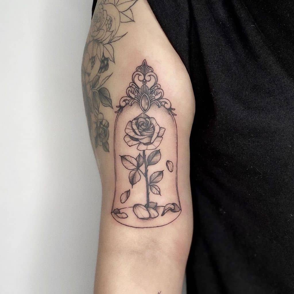 A delicate blackwork tattoo of the Beauty and the Beast rose inside a glass dome, featuring fine details and elegant shading