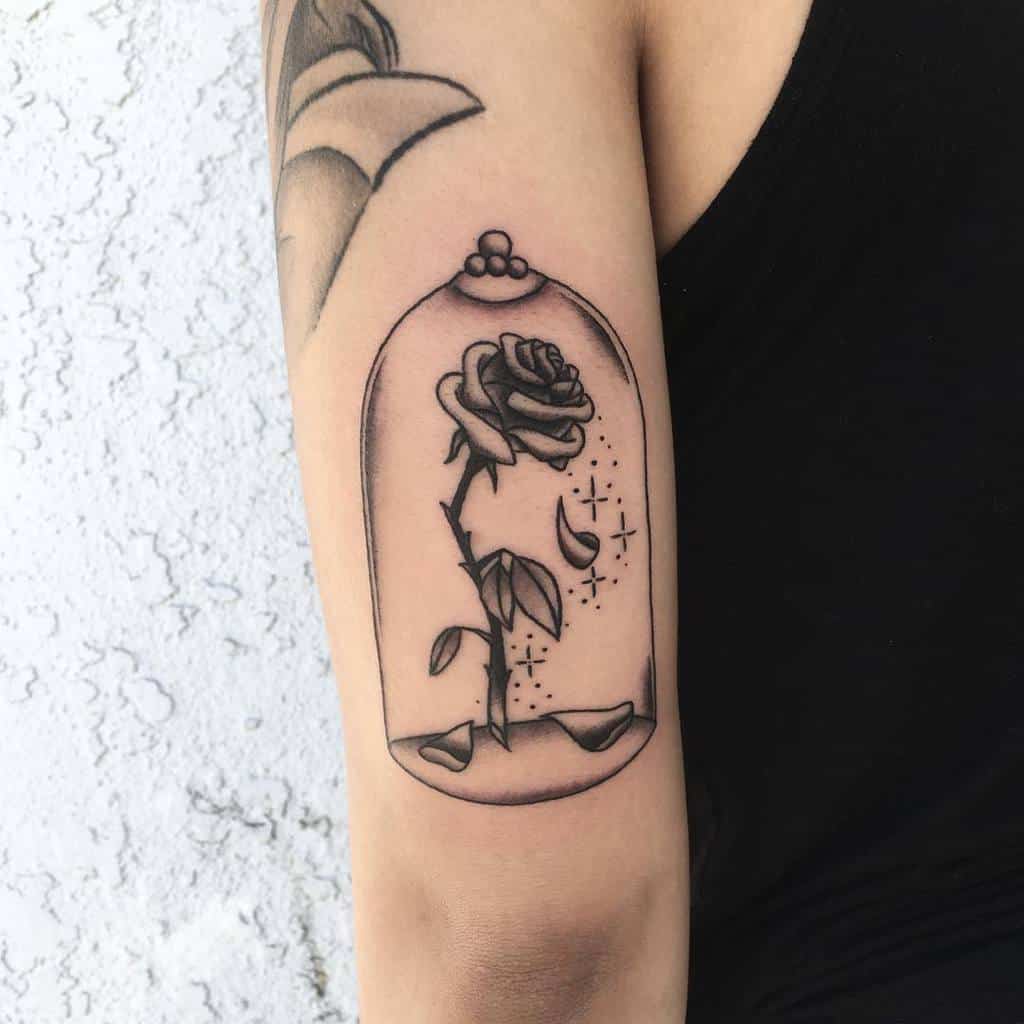 A minimalist blackwork Beauty and the Beast rose tattoo inside a glass dome, with delicate details, floating petals, and sparkling accents