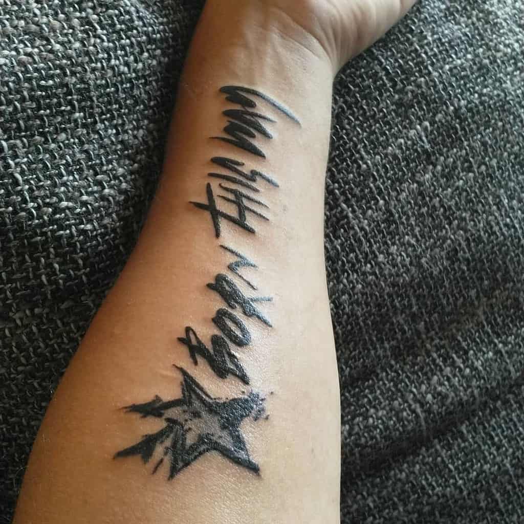 Forearm tattoo featuring 'Born This Way' text in bold lettering with a black star design beneath it