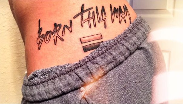 Tattoo on the side of a torso reads "Born This Way" with a rainbow flag equal sign below
