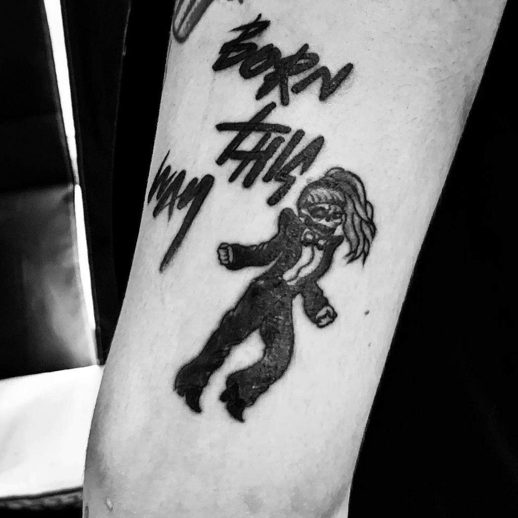 Black and white tattoo of Lady Gaga in a suit with the words "Born This Way" nearby