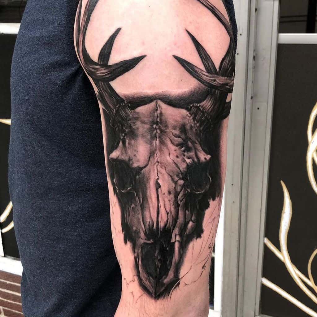 Upper arm tattoo showcasing a beautifully detailed deer skull adorned with striking antlers