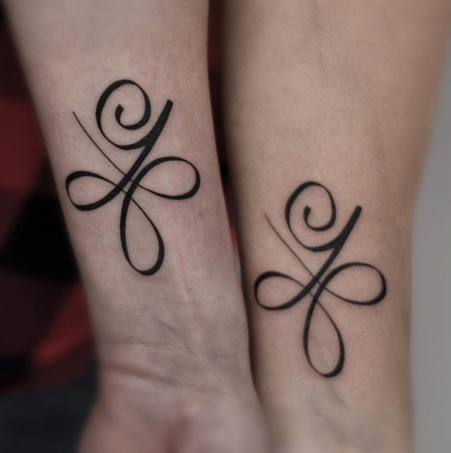 Matching abstract tattoos on two forearms, featuring elegant swirls and loops