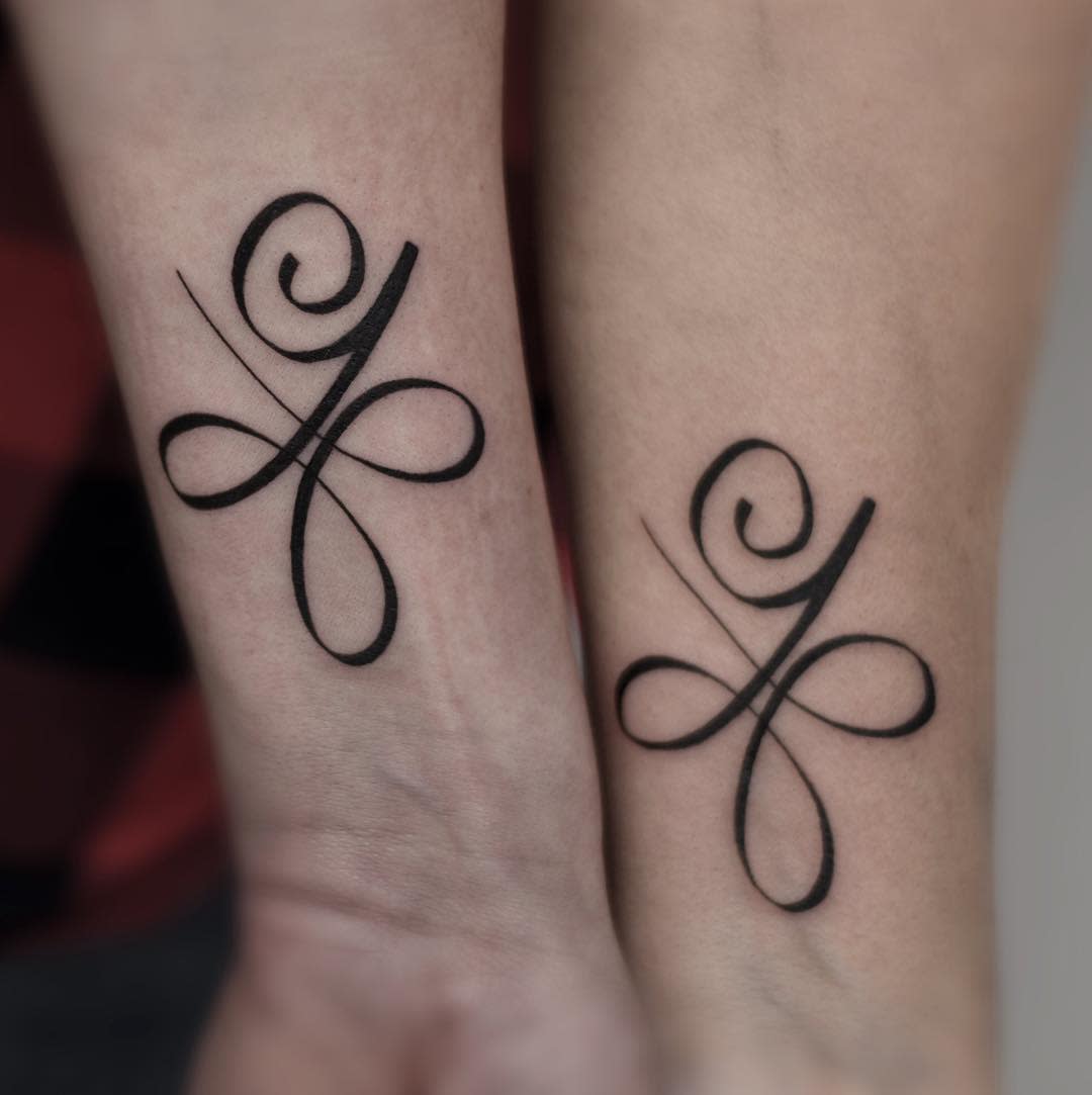 Matching mother-daughter minimalist tattoos featuring intertwined swirls and loops, creating a clean, elegant design
