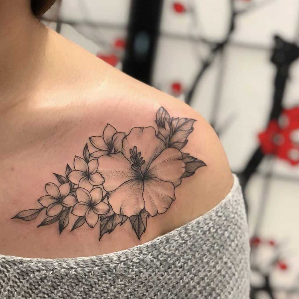 A detailed floral tattoo on a shoulder, featuring hibiscus and other flowers