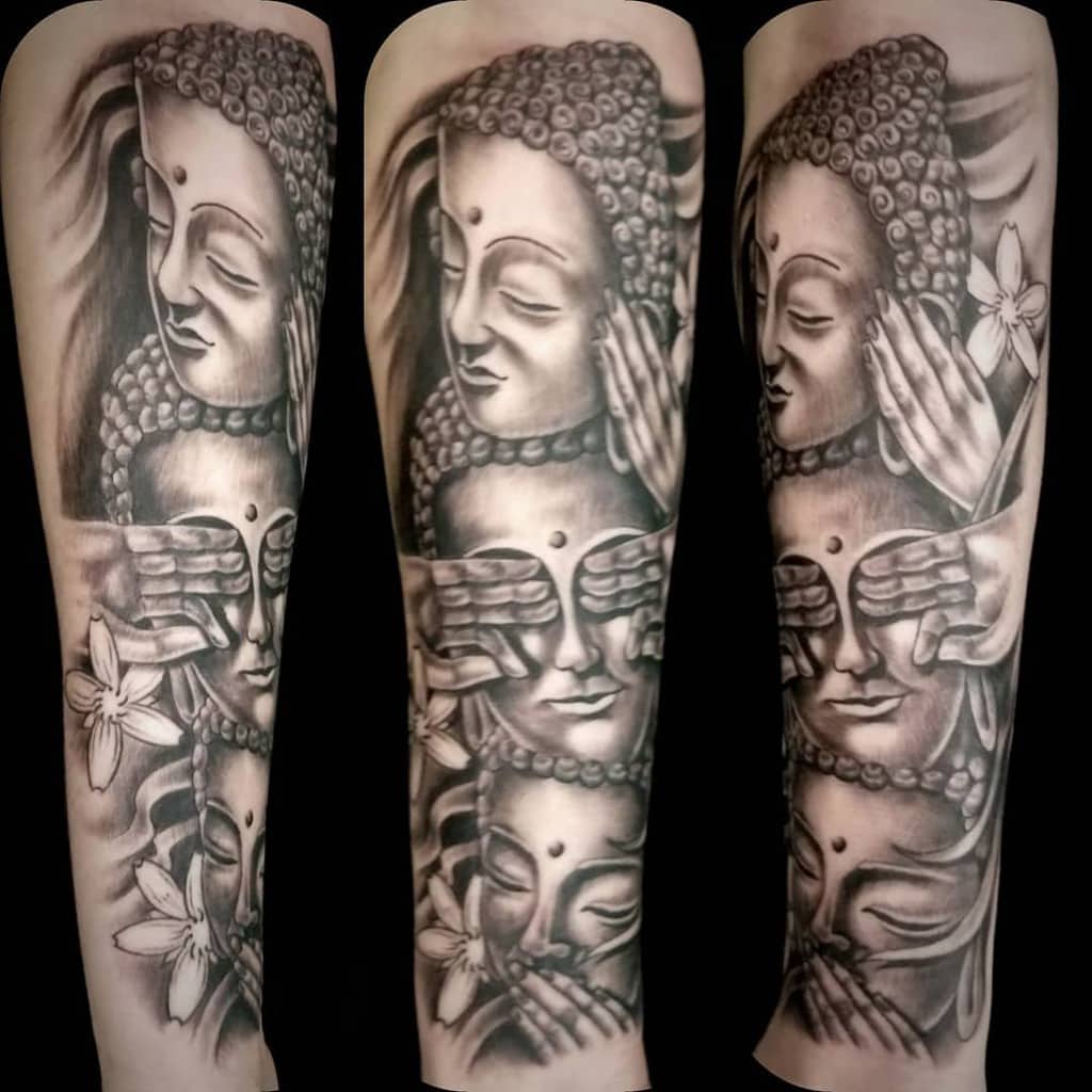 Black and grey tattoo featuring three serene Buddha faces with hands symbolizing 'Hear No Evil, See No Evil, Speak No Evil'