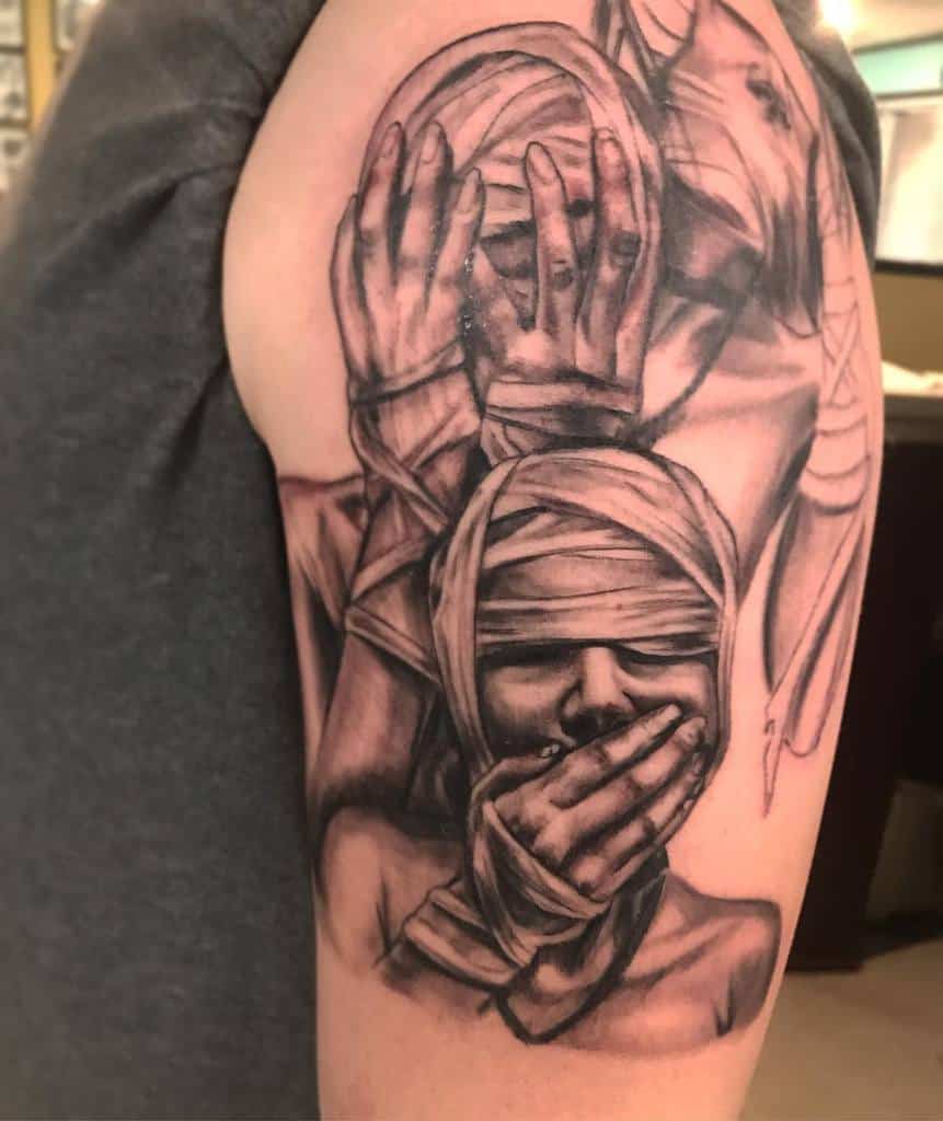 A tattoo of three wrapped figures covering their eyes, ears, and mouth on an arm