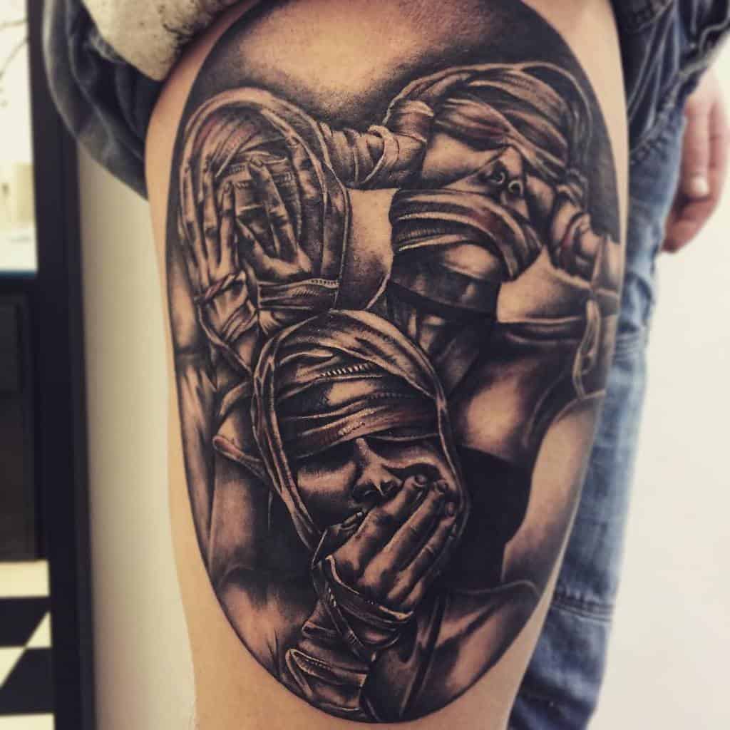 Tattoo of three bandaged faces on a person's arm, each covering eyes, ears, and mouth