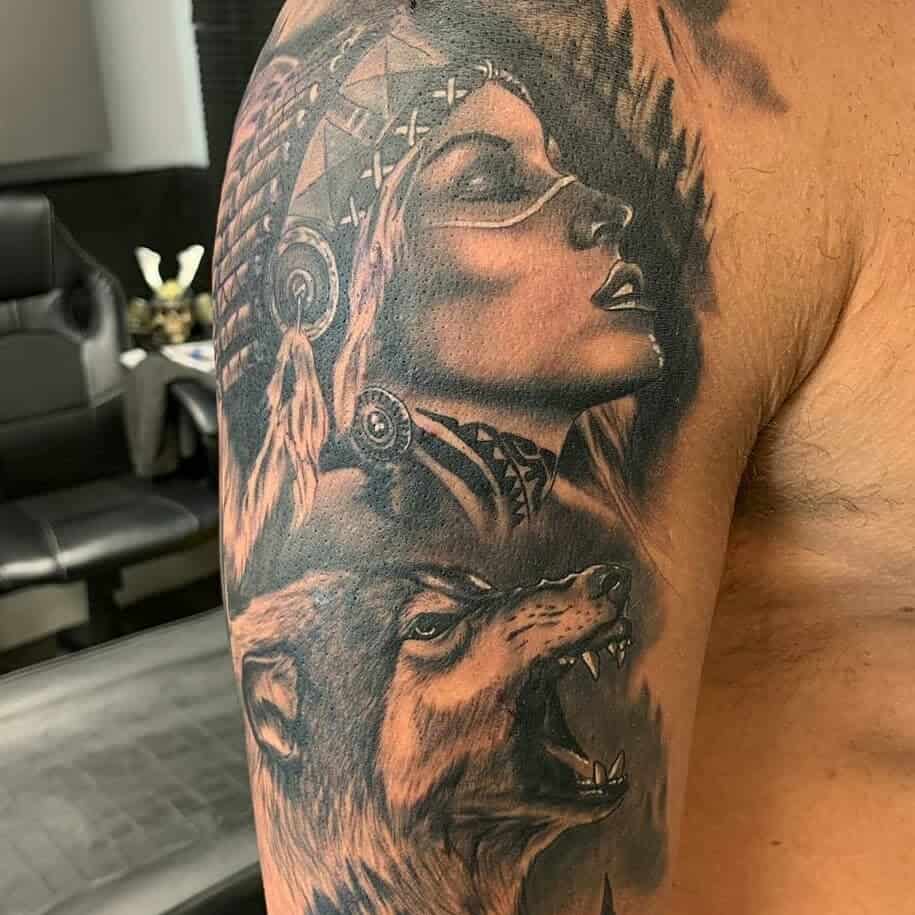 Arm tattoo of a majestic wolf intertwined with the image of a woman in an elaborate headdress, capturing an ethereal connection between wilderness and spirit