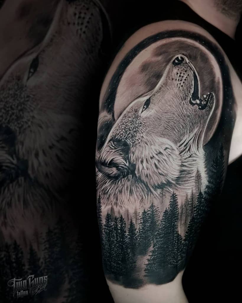 A striking tattoo of a wolf howling in front of a radiant moon, set against a dense forest backdrop, elegantly sprawls across the arm