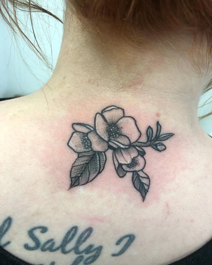 Neck tattoo of flowers with two leaves and stems, above script text on the upper back