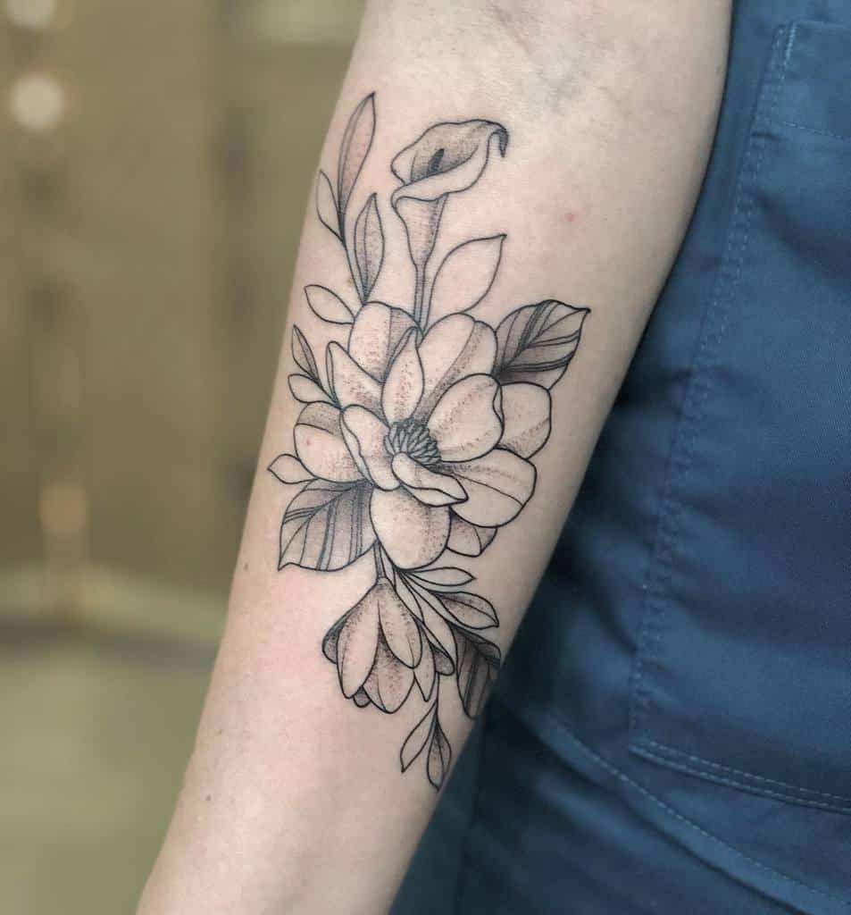A line art magnolia flower tattoo graces a person's forearm, showcasing elegant leaves and delicate petals