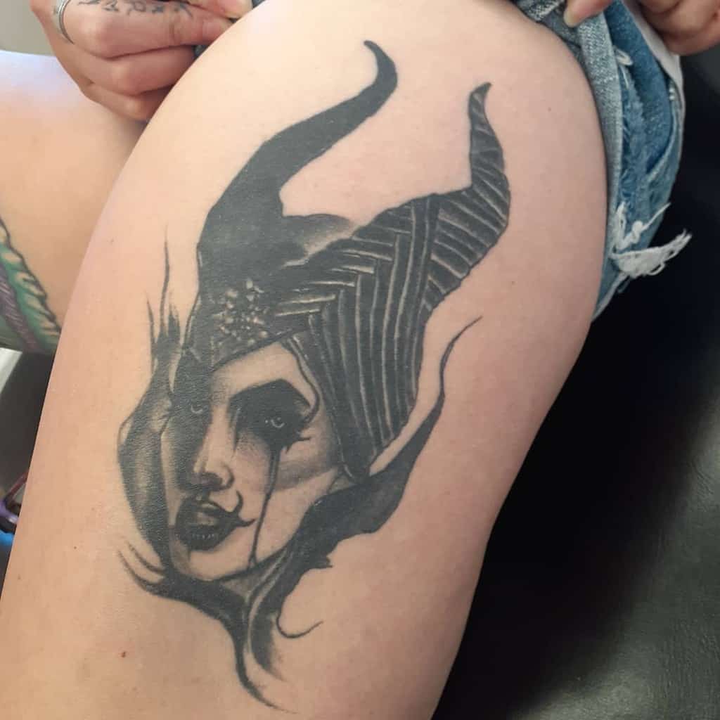 Bold blackwork tattoo of Maleficent on the thigh, featuring dramatic shading and a hauntingly powerful expression