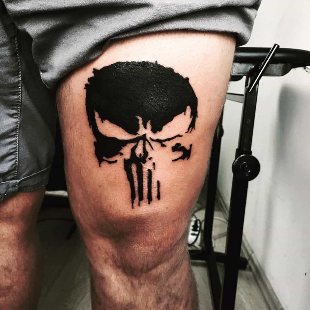 Solid black Punisher Skull tattoo on the thigh, featuring a minimalistic design with sharp lines for a bold, impactful look