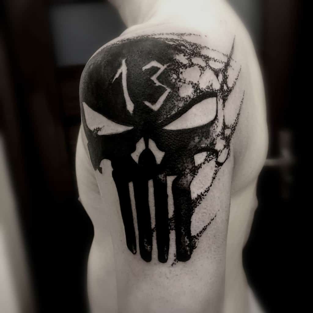 
Punisher Skull tattoo on the shoulder with a bold black design, featuring the number 13 and a web effect for added texture and mystique